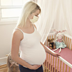 A pregnant woman use surgical mask close her mouth and nose at home