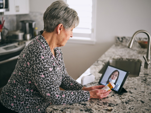 A senior aged woman in her home, talking to a doctor online in a virtual appointment.