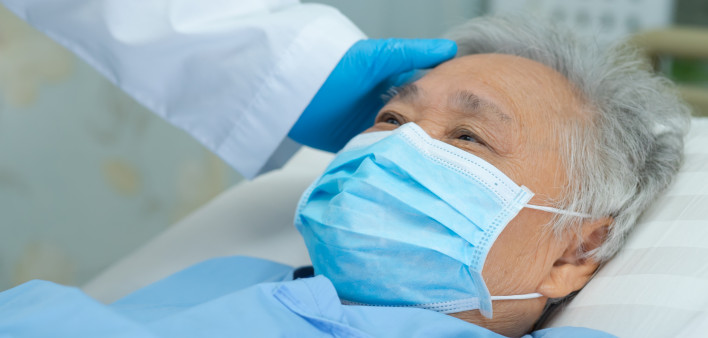 Doctor touching and checking Asian senior or elderly old lady woman patient wearing a face mask in hospital for protect infection and kill Novel Coronavirus Covid-19 virus