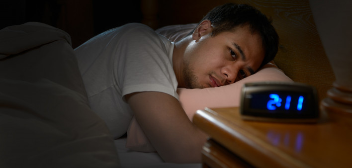 Depressed man suffering from insomnia lying in bed