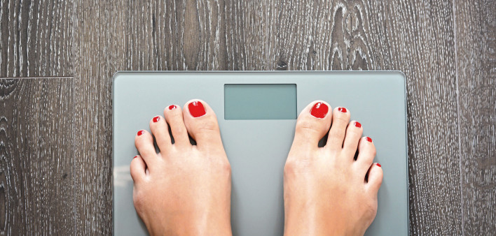 womans feet on scale red toe nails