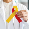 World hepatitis day and HIV/ HCV co-infection awareness with red yellow ribbon in medical doctor hand