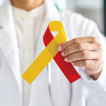 World hepatitis day and HIV/ HCV co-infection awareness with red yellow ribbon in medical doctor hand