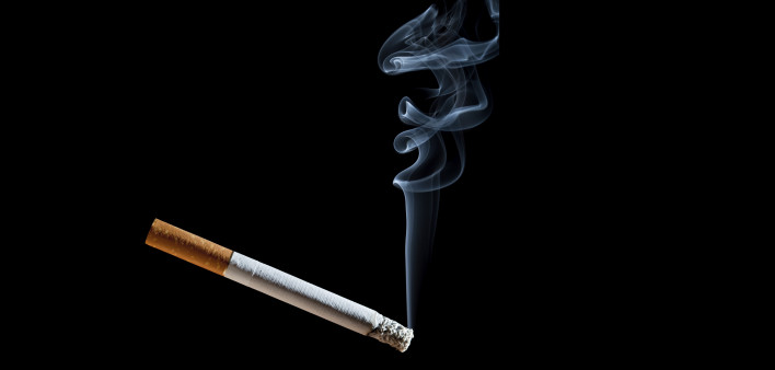 Cigarette with blue smoke on black background