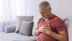 Severe heartache, man suffering from chest pain, having heart attack or painful cramps, pressing on chest with painful expression. Photo of Mature man suffering from chest pain at home during the day.