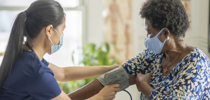 Female medical professional checking senior patient's blood pressur