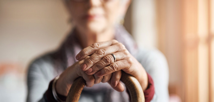 old woman, her hands resting on a cane