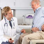 Male Doctor Examining Male senior Patient With Hip Pain