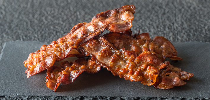 Fried bacon strips on the stone dark board