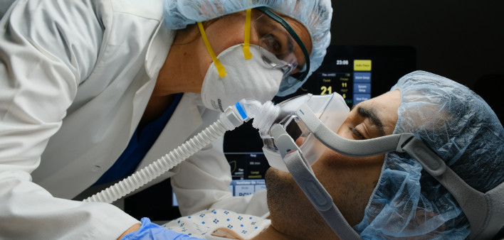 Female caucasian doctor checking on Covid-19 infected patient while connected to a ventilator at a hospital room