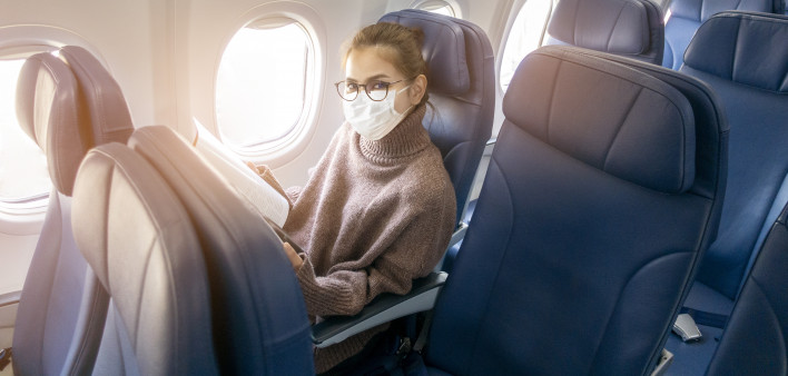 A young woman wearing face mask is traveling on airplane , New normal travel after covid-19 pandemic
