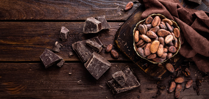 Cocoa beans and chocolate on wooden background