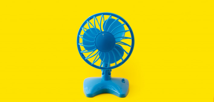 Electric blue plastic fan isolated on yellow background