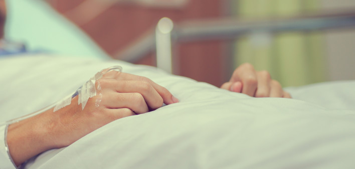 Close up patient man hand with label and drip (IV saline tube) waiting for operation of chemotherapy medical , healthcare and cancer
