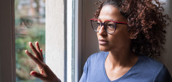 Lonely black woman near window thinking about something girl sad