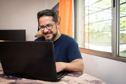 Latino man living with HIV using a laptop