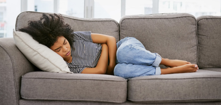 woman girl stomach cramps couch pain