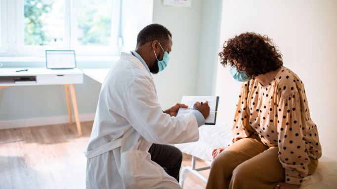 Close up of a doctor doing a medical exam while both him and the patient are wearing protective masks