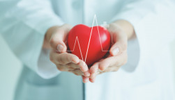 Female medical doctor holding red heart shape in hand with graphic of heart beat, cardiology and insurance concept