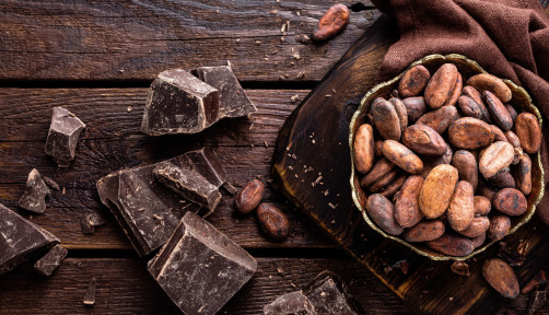 Cocoa beans and chocolate on wooden background