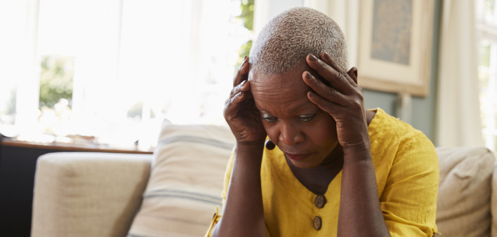 Senior Woman Sitting On Sofa At Home Suffering From Depression
