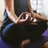 Cropped shot of an unrecognizable woman sitting on a yoga mat and meditating alone in her home