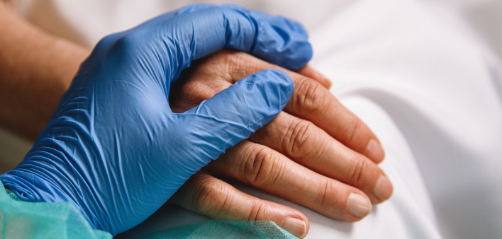 doctor hand with blue glove giving support and love to a patient at hospital. Coronavirus