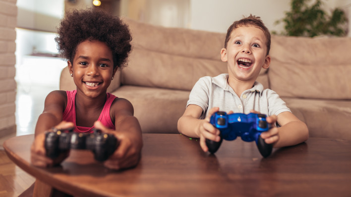 Boy and girl sitting in living room playing video game together