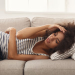woman girl stomach cramps headache pain couch