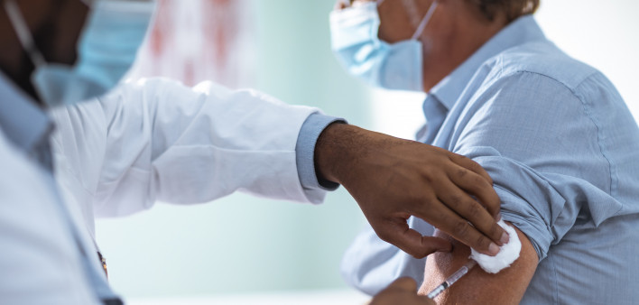 Close up of a mature man taking a vaccine in his doctors office
