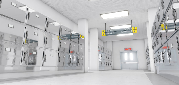 A look down the aisle of fridges in a clean white ward in a mortuary