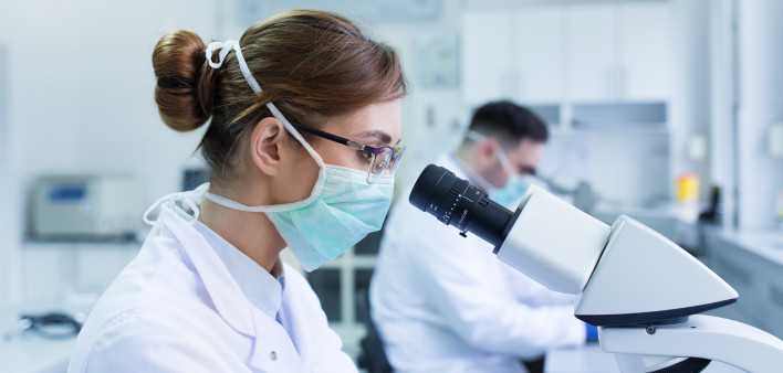 Team of experienced biologists working on microscopes in laboratory