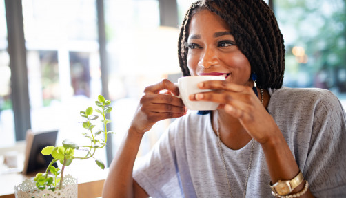Beautiful young african woman enjoying a cup of coffee in coffee shop