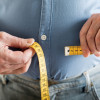 man's hands holding tape measure aound belly
