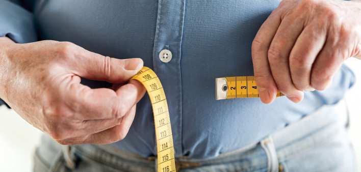 man's hands holding tape measure aound belly