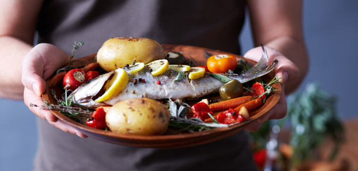 man holding plate of food fish