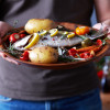 man holding plate of food fish