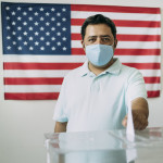 Middle aged Mexican man with protective face mask voting on election day