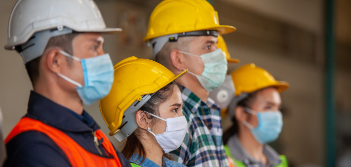 Workers wear protective face masks for safety in machine industrial factory.