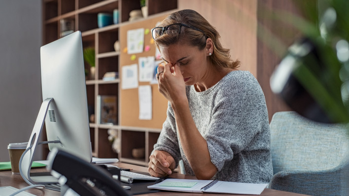 Exhausted businesswoman having a headache in modern office.