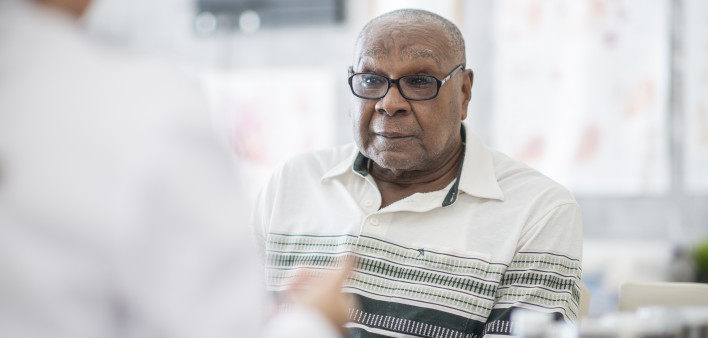 An African American man wearing eyeglasses sits in a doctor's office