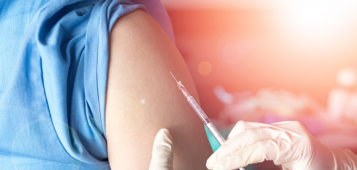 Vaccination healthcare concept. Hands of doctor or nurse in medical gloves injecting a shot of vaccine to a man patient.