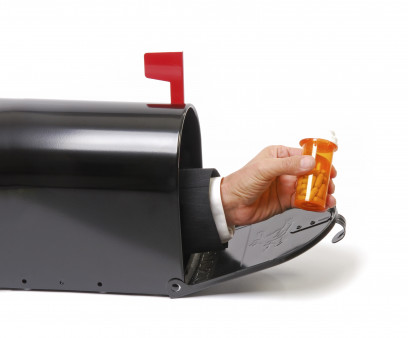 a hand holding a prescription coming out of a mailbox