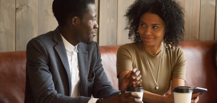 African man and woman talking flirting sitting at coffeehouse table