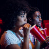 Young couple watching a film at the cinema African American