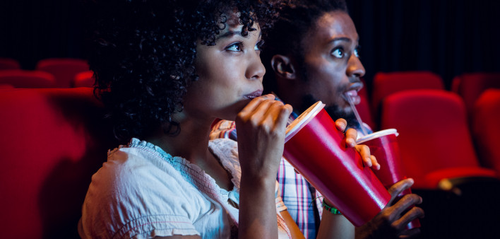 Young couple watching a film at the cinema African American