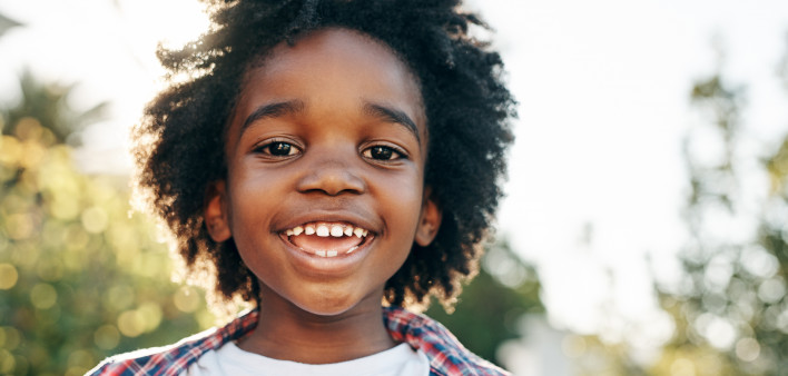 Portrait of a cheerful little boy smiling at the camera outside during the day