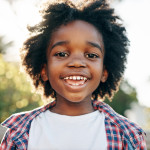 Portrait of a cheerful little boy smiling at the camera outside during the day