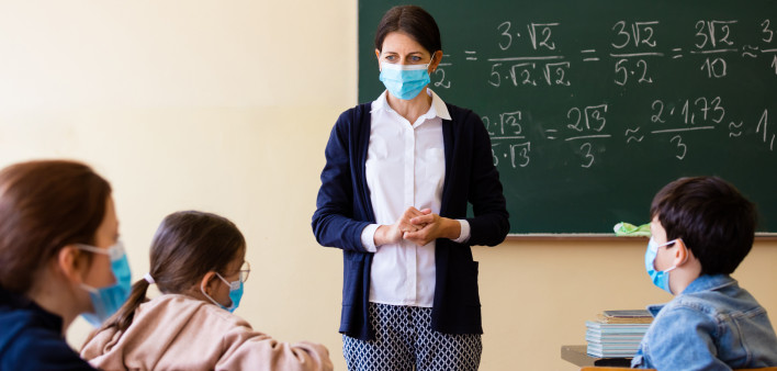 teacher wearing mask in classroom child wearing mask covid-19