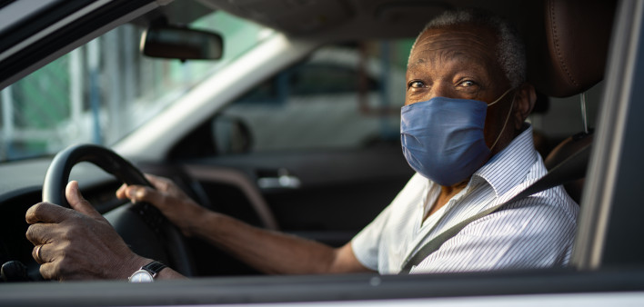 Portrait of senior african man driving a car with face mask
